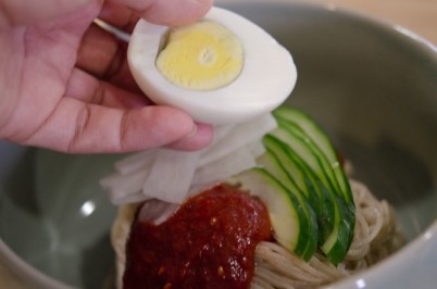 Adding egg to Korean cold noodle